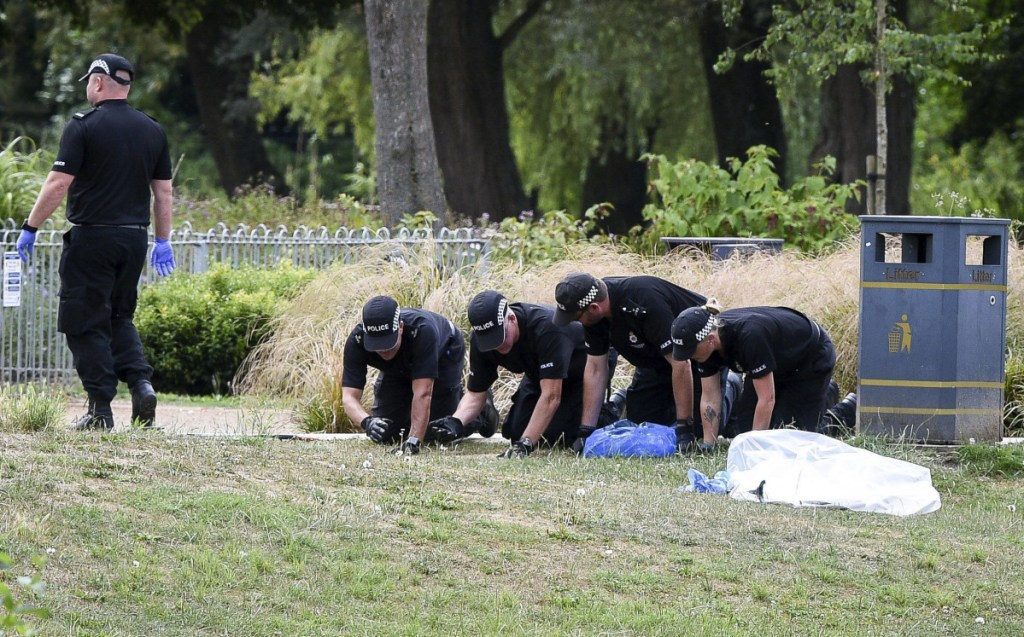 Police conduct fingertip searches of Queen Elizabeth Gardens in Salisbury, which British woman Dawn Sturgess visited before she fell ill after being exposed to nerve agent Novichok. Senior coroner David Ridley opened an inquest into the poisoning death of Sturgess on Thursday, but said the cause of death won't be given until further tests are completed. (Ben Birchall/PA via AP)