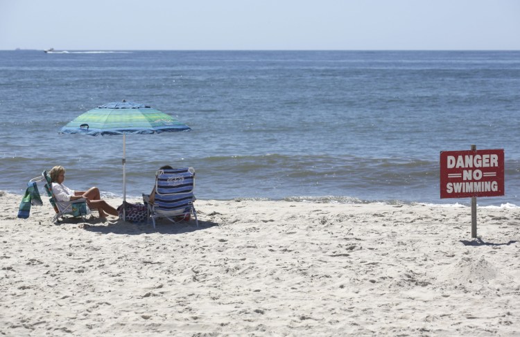 A "no swimming" sign is seen near Ocean Beach on Fire Island in Islip, N.Y. on Thursday.