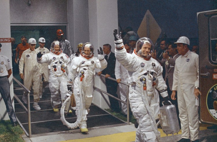 In this July 16, 1969, file photo, Neil Armstrong waving in front, heads for the van that will take the crew to the rocket for launch to the moon at the Kennedy Space Center.
