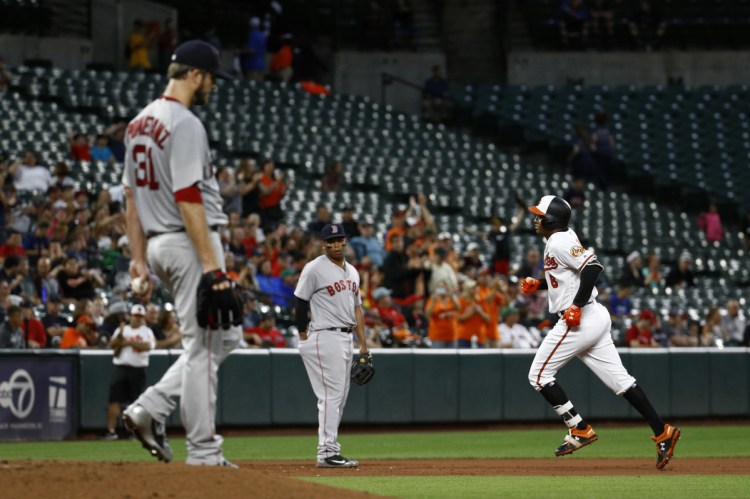 Baltimore's Jonathan Schoop, right, rounds the bases past Boston Red Sox starting pitcher Drew Pomeranz, front left, and third baseman Rafael Devers after hitting a two-run home run in the third inning of the Orioles' 7-6 win over the Red Sox on Tuesday in Baltimore.