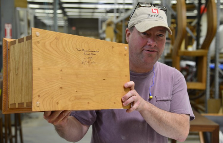 Thos. Moser cabinetmaker Andy Pinkham, who himself is running Saturday's Beach to Beacon 10K, with one of the handcrafted boxes presented to winners.