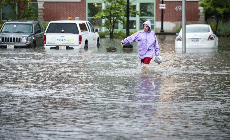 Jessica Morgan sloshes down Maple Street in Lewiston as she makes her way to work Thursday afternoon during a downpour that flooded streets, businesses and houses throughout the area, which received more than an inch of rain in less than two hours.