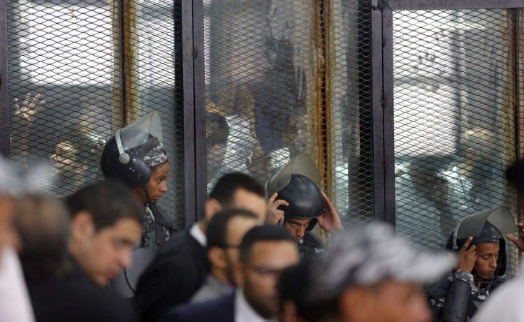 Police guard 739 defendants at a soundproof glass cage inside a makeshift courtroom in Tora prison in Cairo on Saturday. Egypt's state-run media says a court has sentenced 75 people to death, including top figures of the outlawed Muslim Brotherhood group, for their involvement in a 2013 sit-in.