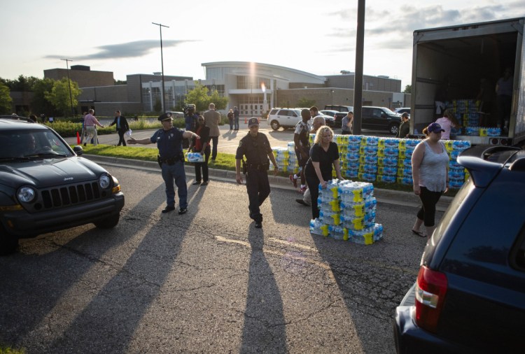 Emergency response teams hand out free bottled water to residents at the Parchment High School in Parchment, Mich., on Friday. 