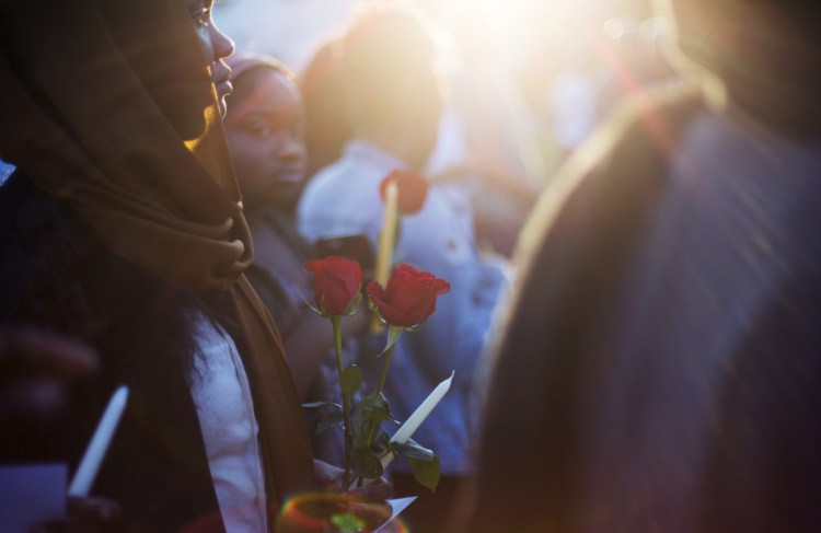 Samar Ahmed of Portland holds roses during Tuesday night's vigil for Patrick Lobor.