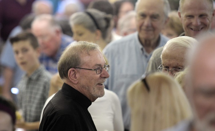 Hundreds come to give the Rev. Francis Morin, center, well wishes Sunday in the basement of St. Augustine's Church in Augusta before his retirement.