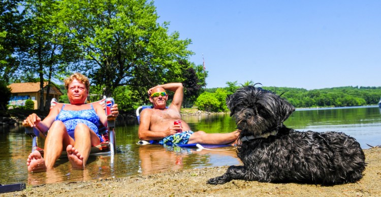 Tina Tarbox, left, David Tarbox and their dog Deliah cool off in Maranacook Lake in Winthrop on Thursday, as the temperature soared above 90 degrees. The nearby town beach was crowded too as people tried to beat the heat.