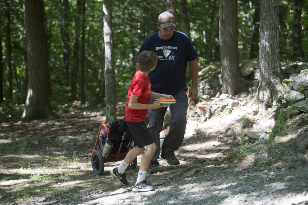 Nate Delisle, 11, gets some pointers from his caddie Bobby Harris during a Pro Disc Golf Association qualifier at Burnsboro Disc Golf Course on Saturday in Vassalboro.