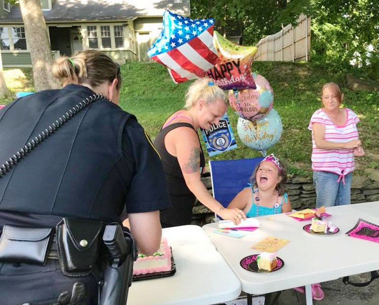 Larriah Binns, 8, of Sidney laughs with Augusta Police Officer Carly Wiggin Sunday at an impromptu birthday party on Murray Street. The celebration was arranged by Augusta police after they learned that none of Larriah's friends came to the party a day earlier. Helping Larriah is her mother, Angelique Binns, and her grandmother, Julie Ladson.