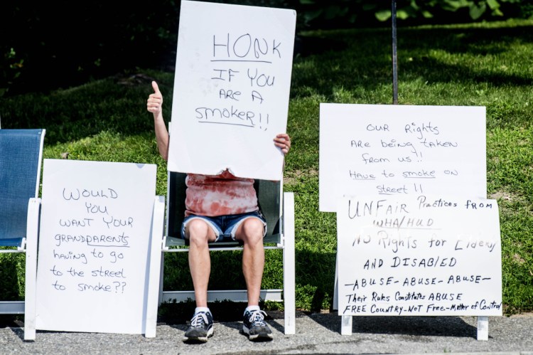 Misty LaCroix, a resident of the Elm Towers, gives the thumbs-up sign July 3 to a pro-smoking horn honker for supporting her protest of a smoking ban recently instituted by Waterville Housing Authority.