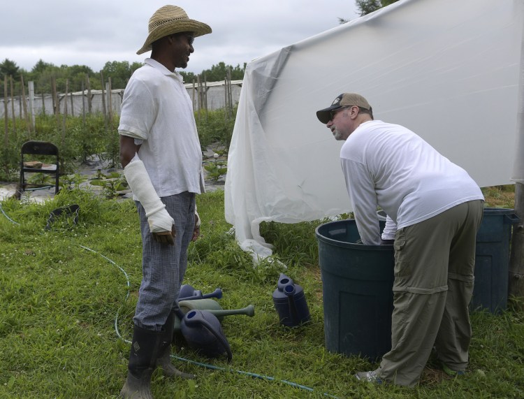Craig Hickman, left, speaks Sunday with his neighbor, John Branning, who volunteered to fertilize vegetables at the Winthrop farm Hickman operates with his husband, Jop Blom. Hickman is welcoming the assistance of volunteers at Annabessacook Farm while he recovers from burns he sustained last week.