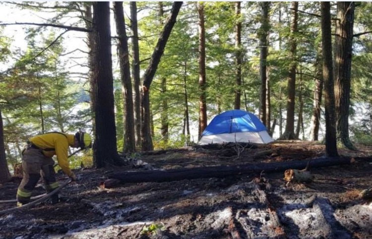 Members of the Belgrade Fire Department and Maine Forest Service knock down a fire near Hamilton Pond in Belgrade on Friday evening, July 13. Authorities say it resulted from an illegal campfire.