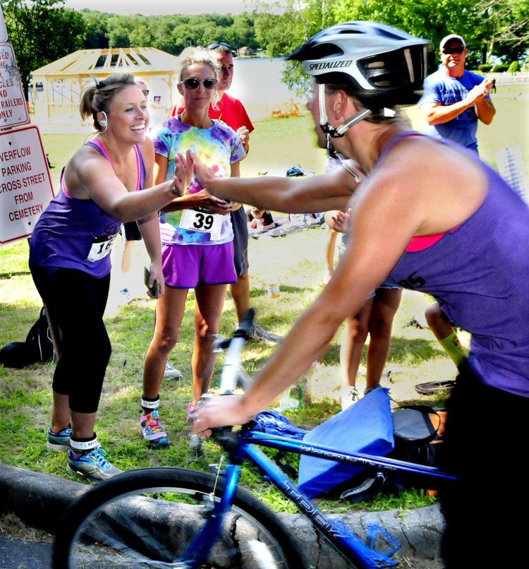 Runner Jess McKay, left, and cyclist Adrian Phair hand-off at the boat landing in Oakland as they compete in the OakFest triathalon in their respective sports on July 23, 2017.
