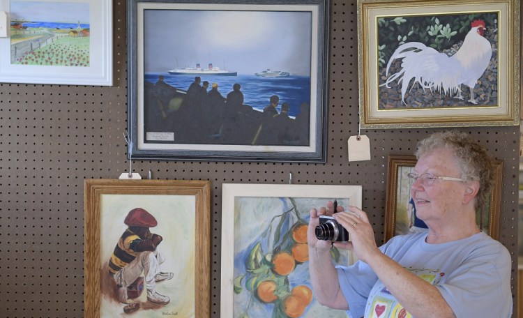 Marilyn Stinson photographs the display she arranged Tuesday for the Enterprise Grange, of Richmond, in the exhibition hall at the Pittston Fairgrounds. The Pittston Fair starts Thursday and wraps up Sunday.