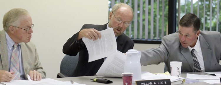 Maine Ethics Commissioners Richard Nass, left, Chairman William Lee III and Bradford A. Pattershall examine a document Wednesday while hearing a Clean Elections complaint from House District 110 Republican candidate Mark André, of Waterville, at the State Ethics Commission in Augusta.