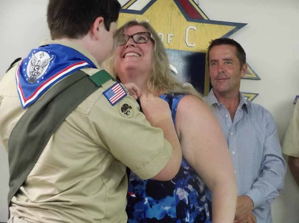 Eric McDonnell pins the Mother's Pin on his mom Audrey McDonnell in recognition of her support during his Scouting career while his dad Patrick looks on.