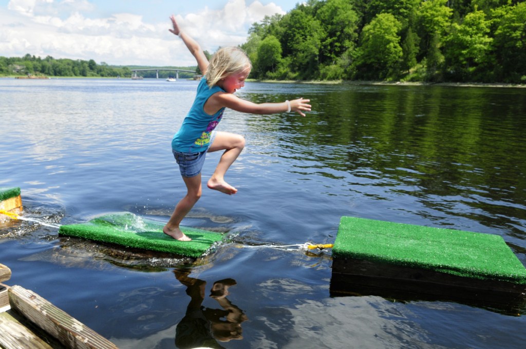 Emmy Foster, 7, of Richmond, scrambles over a string of floating lobster crates strung between two docks on July 23, 2016, in the Kennebec River as part of the town's annual Richmond Days festivities.