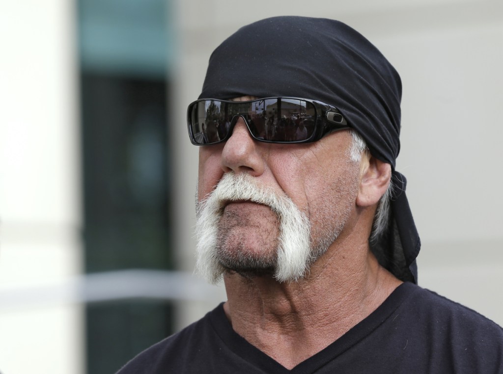 In this October 2012 photo, reality TV star and former pro wrestler Hulk Hogan, whose real name is Terry Bollea, looks on as his attorney speaks in Tampa, Florida. World Wrestling Entertainment Inc. has reinstated Hogan to its Hall of Fame, three years after he was found to have used racial slurs in a conversation caught on a sex tape.