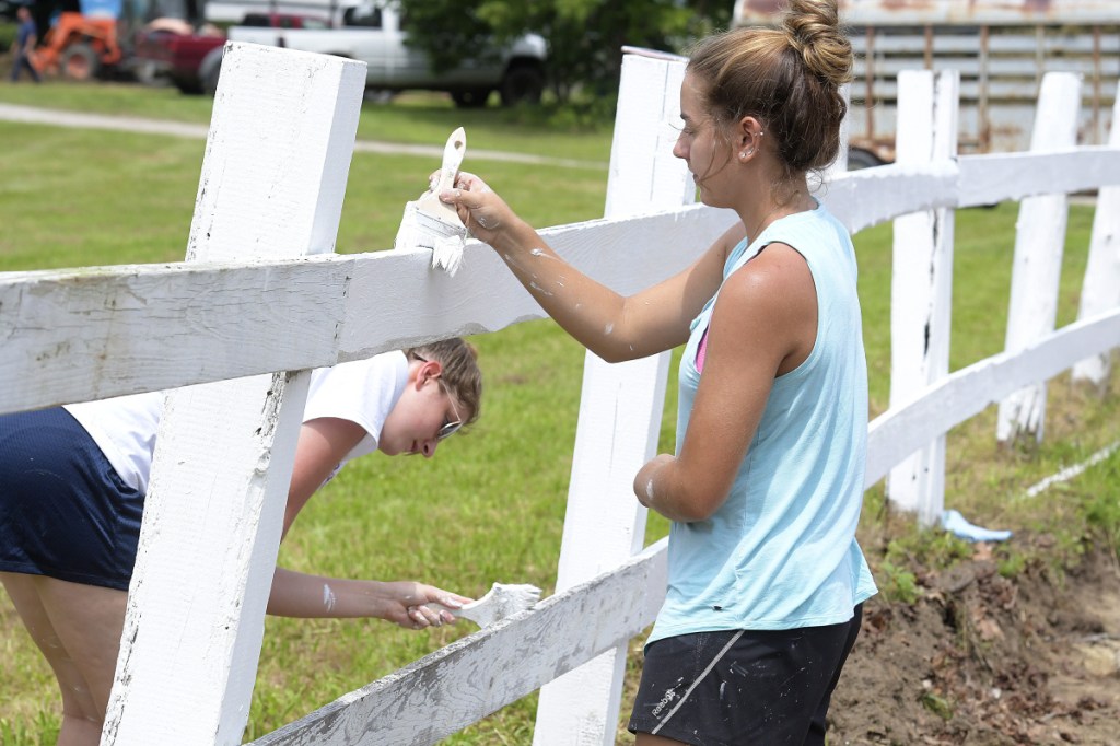 Kaeti Butterfield, left, and Abby Ferland whitewash a fence Tuesday near the horse pen at the Monmouth Fair as they touch up the border between the parking area and the pulling ring. The Monmouth Academy seniors were fulfilling a community service requirement to graduate. The Cochnewagon Agricultural Association's four-day annual fair opens Wednesday with a midway and animal exhibitions.