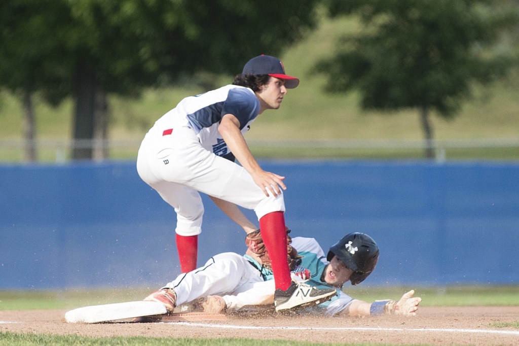 Staff photo by Michael G. Seamans 
 Messalonskee's Carter Lambert slides safely under the tag of Hampden's Michael Beaulieu at third base in the Junior American Legion State Tournament on Tuesday at Mansfield Stadium in Bangor.