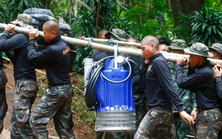 Soldiers carry a pump Friday to help drain the  floodwater in a cave where 12 boys and their soccer coach have been trapped since June 23.. More rains are forecast to hit the region within days. 