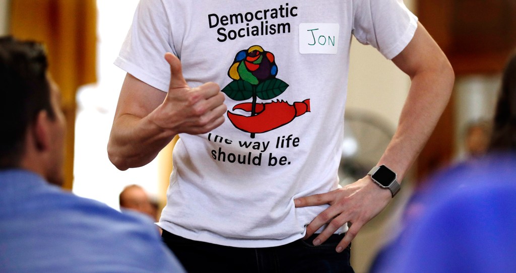 Jon Torsch, center, wears a T-shirt promoting democratic socialism during a gathering of the Southern Maine Democratic Socialists of America at City Hall in Portland. 