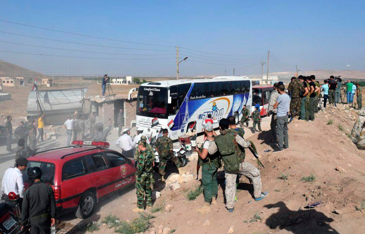 This photo released by the Syrian official news agency SANA, shows Syrian troops, journalists and civilians watching as buses evacuate people from the two pro-government villages of Foua and Kfarya, at Tel el-Eis, the crossing between Aleppo and Idlib provinces in Syria on Thursday.