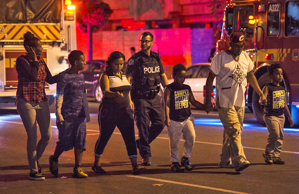 Police escort civilians away from the scene of a shooting Sunday night in Toronto. 