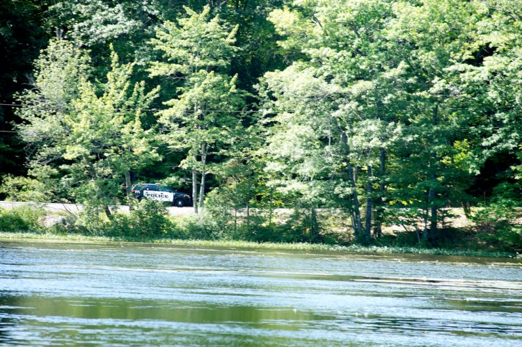 An officer with the Auburn Police Department drives down the Holbrook Road alongside The Basin on Sunday morning. (