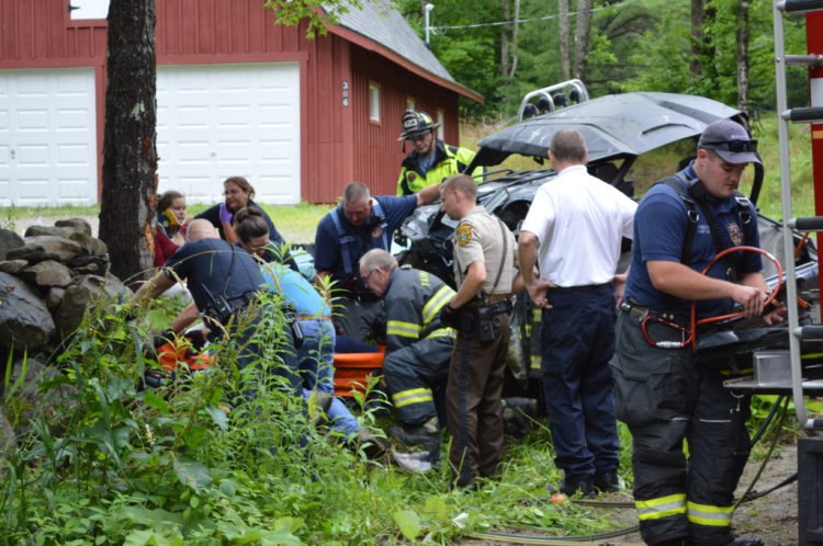 Emergency responders work on a 14-year-old girl who was trapped under a side-by-side recreation vehicle that struck a tree and rolled over on Monday afternoon on Owen Mann Road in West Farmington. The driver and her 17-year-old passenger were injured. 