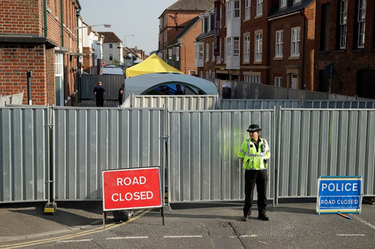A police officer guards metal fencing erected as tents are set up behind where two people cam in contact with a deadly nerve agent.,  in Salisbury, England.