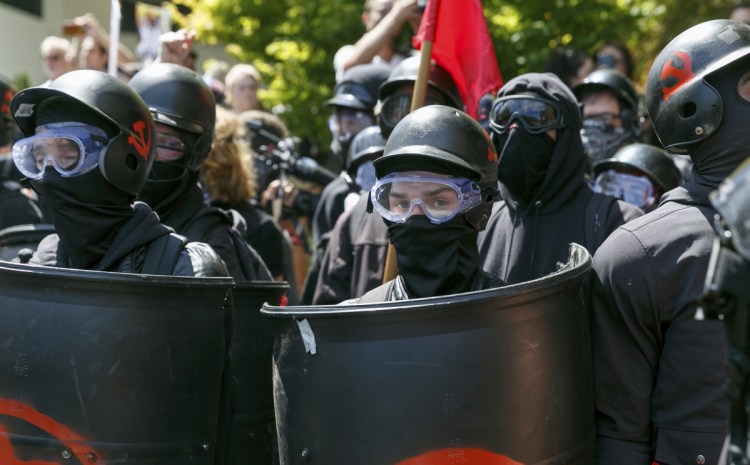 Dressed for battle in helmets and protective gear, counterprotesters prepare to clash Saturday with Patriot Prayer members at a rally in Portland, Ore. Officers formed a wall in the middle of a road to try to keep the groups separated.