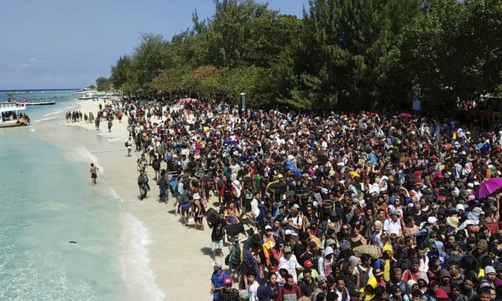 Tourists affected by a strong earthquake wait to be evacuated on Gili Trawangan Island in Indonesia on Monday.