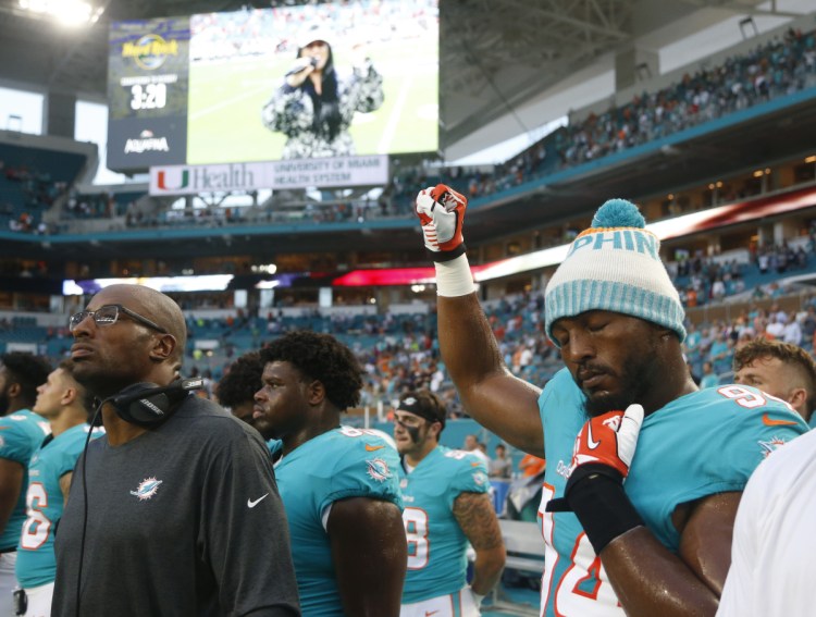 Miami Dolphins defensive end Robert Quinn raises his right fist during the singing of the national anthem, before the team's NFL preseason football game against the Tampa Bay Buccaneers on Thursday in Miami.