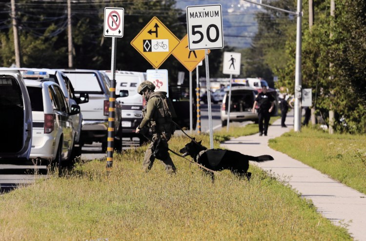 Police officers survey the area of a shooting in Fredericton, New Brunswick, on Friday.  Fredericton police say two officers were among four people who died in a shooting in a residential area on the city's north side.