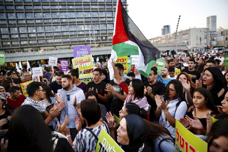 Israeli Arabs hold a Palestinian flag during a protest against the Jewish nation bill in Tel Aviv on Saturday. The recently passed law enshrines Israel's Jewish character and downgrades the standing of Arabic from an official to a "special" language.