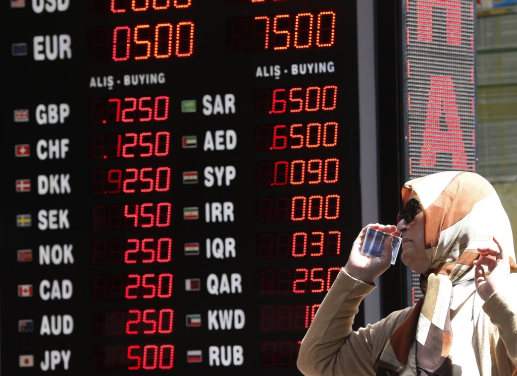 A woman checks the currency exchange rates at a shop in Istanbul on Monday. The Turkish lira tumbled another 7 percent Monday as the central bank's measures failed to restore investor confidence.