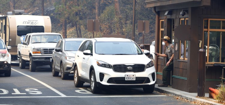 Park Ranger Alex Martinez passes out maps and directs visitors at the Highway 140 gate as Yosemite National Park reopens Tuesday in California after a nearly three-week closure caused by smoke from nearby wildfires.