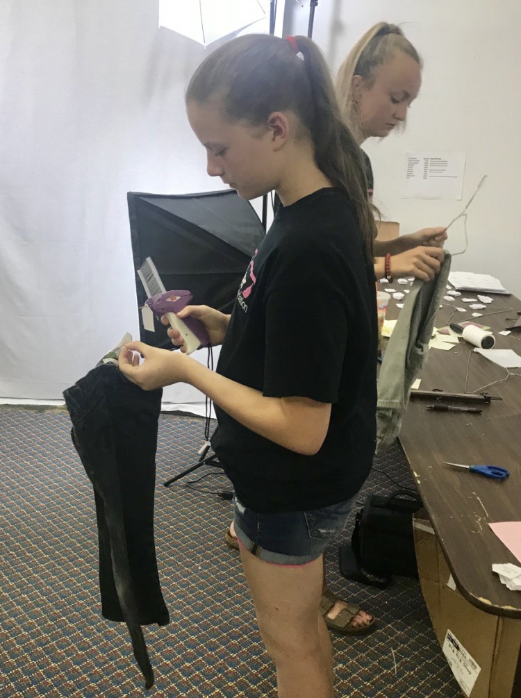 Mallory Gordon, 12, foreground, and Molly Littlefield, 14, tag and size clothes at the Pink Feather Foundation in Oxford.