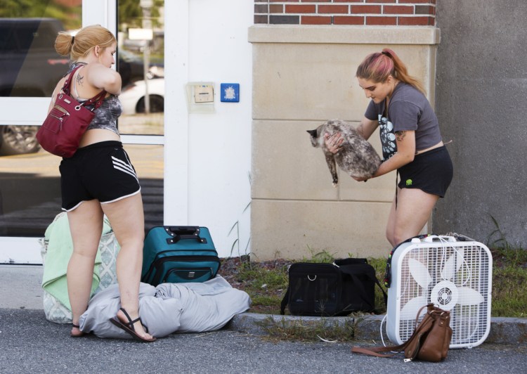 Southern Maine Community College sophomores Olivia Treadwell and Lauryn O'Connor wait for a ride to transport their belongings away from the Spring Point Residence Hall on Sunday because of a mold infestation.