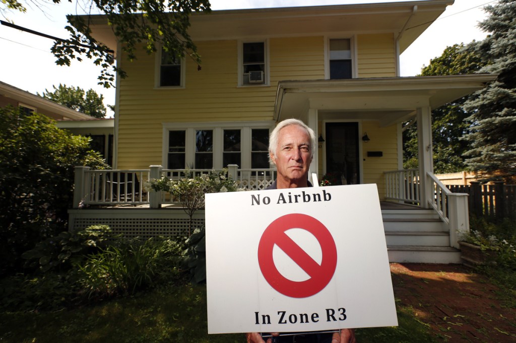 Tom Sidar of Bradley Street holds a lawn sign in August calling for an end to short-term rentals in residential zones.