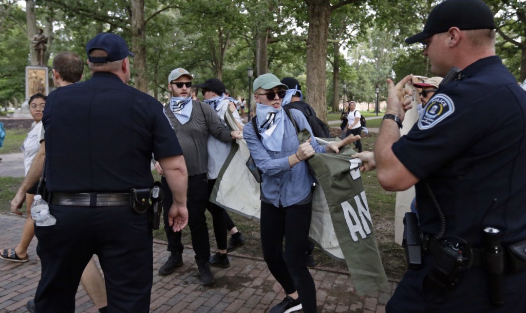 Police try to take a banner from protesters as people gather during a rally to remove the confederate statue known as Silent Sam.