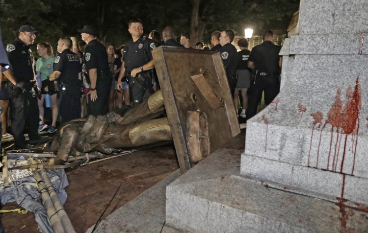 Police stand guard after the confederate statue known as Silent Sam was toppled by protesters on campus at the University of North Carolina in Chapel Hill, N.C., Monday night.