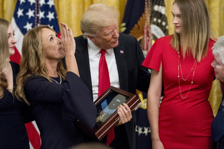 Valerie Nessel, second from left, accompanied by family members, blows a kiss to the sky as she accepts the Medal of Honor from President Trump for her husband, Air Force Tech. Sgt. John A. Chapman, awarded posthumously for conspicuous gallantry, during a ceremony in the East Room of the White House in Washington on Wednesday.