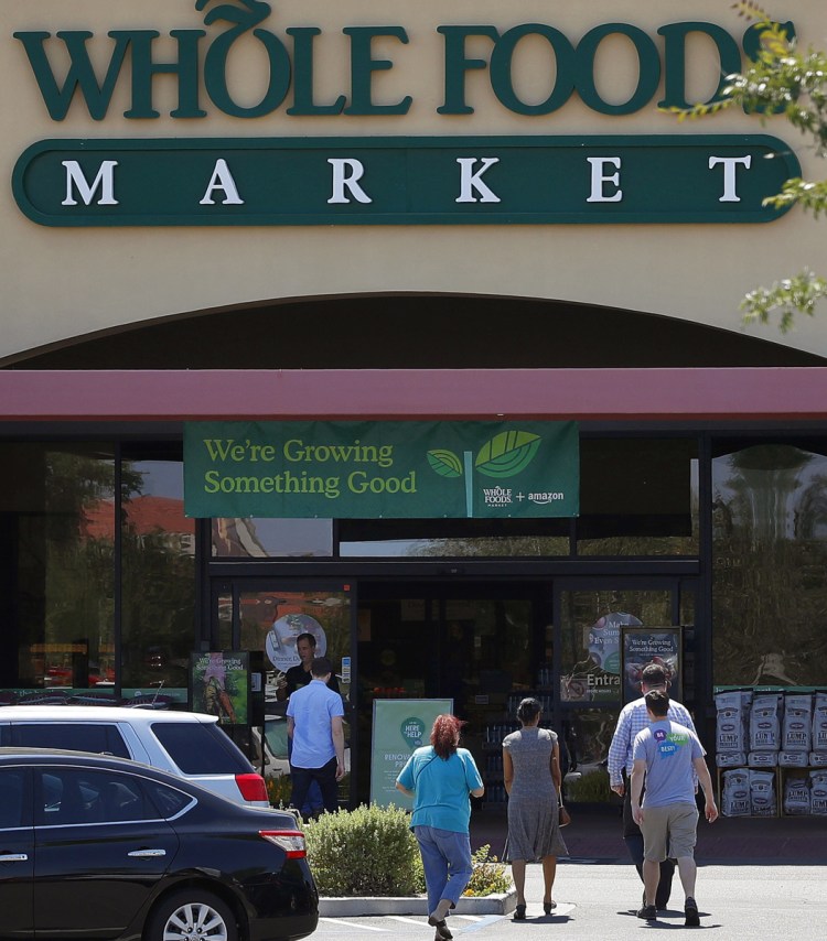Shoppers come and go from a Whole Foods Market in Chandler, Ariz., in 2017. Amazon moved swiftly to say it planned to cut prices on bananas, eggs, salmon, beef and more.