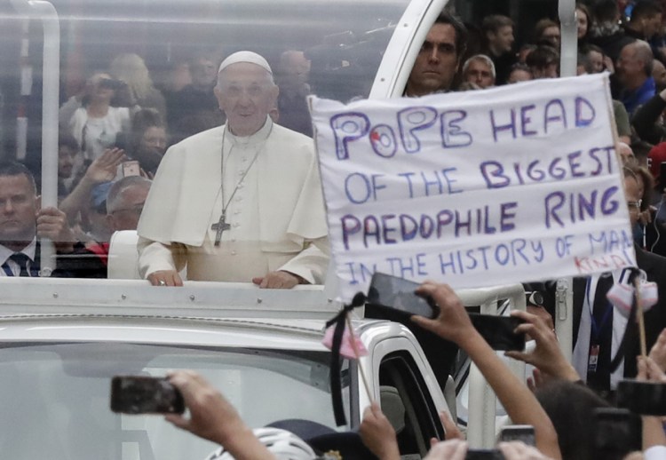 Pope Francis passes by a banner of a protester as he leaves St Mary's Pro-Cathedral in Dublin on Saturday.