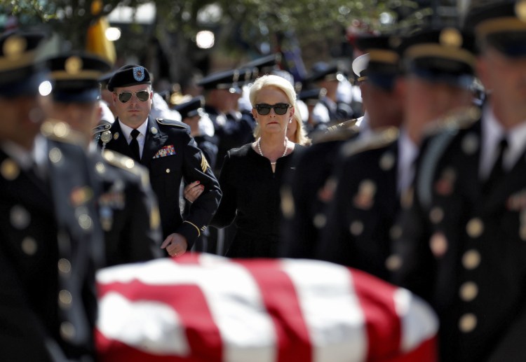Cindy McCain escorted by her son, Jimmy McCain, left, follow military personnel carrying the casket of Sen. John McCain, R-Ariz., into the Capitol rotunda for a memorial service on Wednesday at the Capitol in Phoenix.
