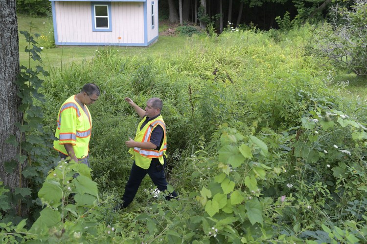 Augusta fire Lt. Brian Chamberlain, right, confers Wednesday with Maine DEP hazardous spill technician Jon Woodard in a small stream where the agencies investigated a heating oil spill.