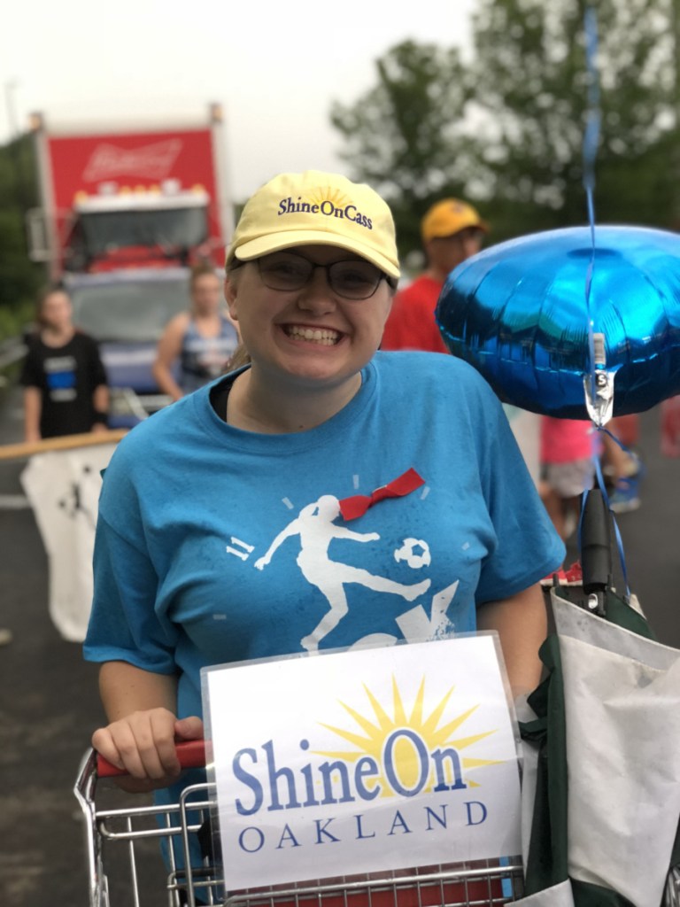 Anya Fegal helps collect cereal boxes in one of the ShineOnCass shopping carts in the Oakfest Parade July 27. More than 150 boxes of cereal were donated to help feed local kids this summer. The event was organized by the ShineOnCass Foundation.