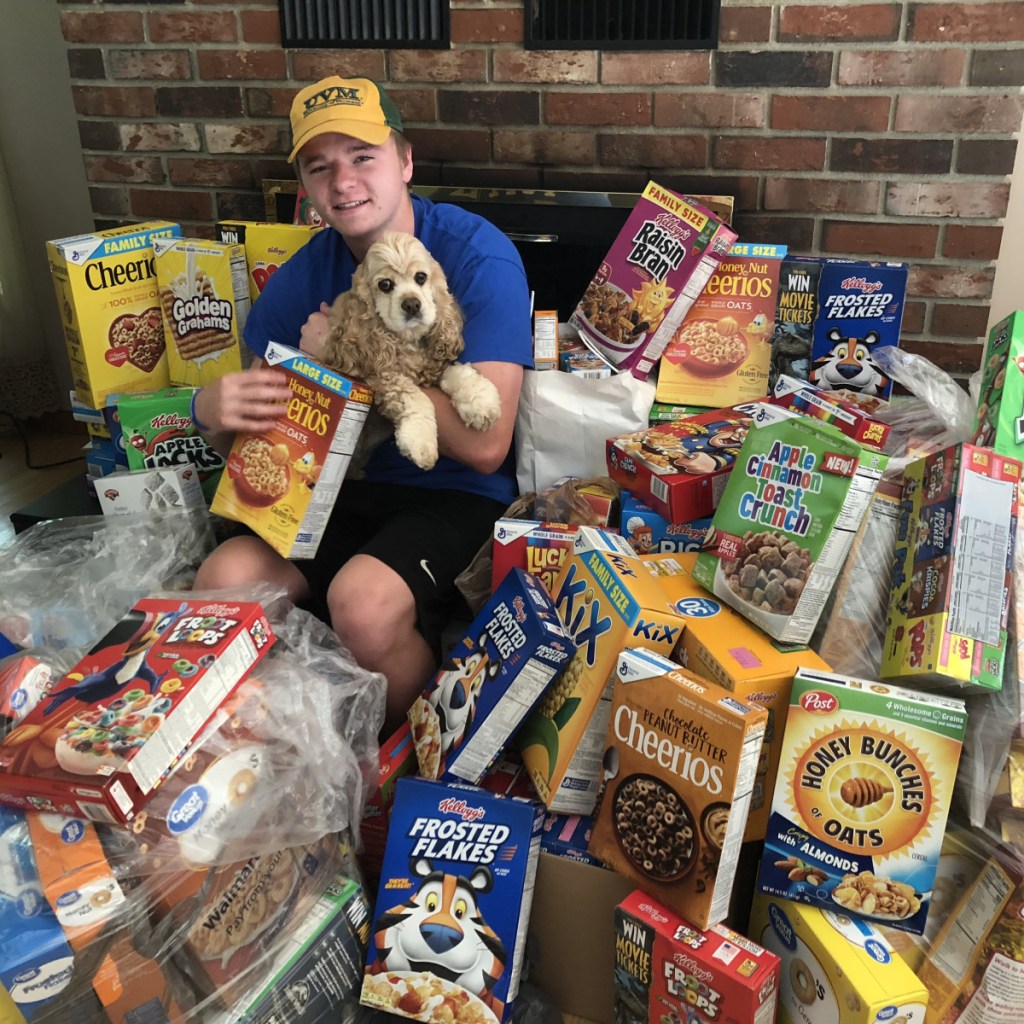 Colby Charette and his dog Sadie sit among the more than150 boxes of cereal collected at Oakfest's first ShineOn Oakland Day in support of local kids. The cereal drive was organized by the ShineOnCass Foundation to support local families through the Oakland Food Pantry.